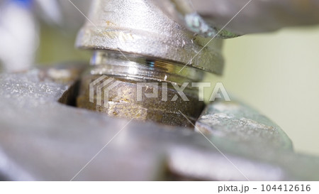 tightening the threaded connection of plumbing pipes with a wrench 104412616