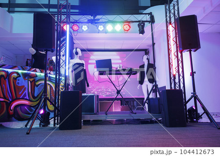 Dj controller on stage for discotheque in empty nightclub with no people. Electronic musician console equipment, loudspeakers and spotlights for live music concert in dark club. 104412673