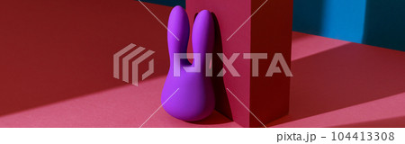 Violet dildo vibrator for clitoris with pink gift box on colored background. Sex toy for adult 104413308