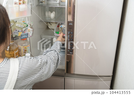 【冷蔵室からトレイを取り出す主婦】 104413555