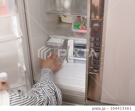 【冷蔵室から給水タンクを出す主婦】 104413561