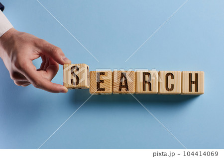 Magnifier and search word written on cube over wooden background 104414069