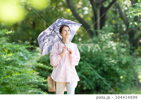 日傘をさして歩くシニア女性 日傘をさして歩くシニア女性 104414899