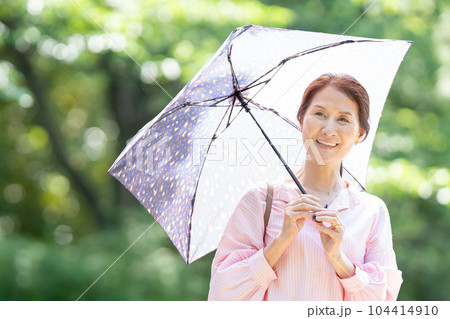 日傘をさして歩くシニア女性 104414910