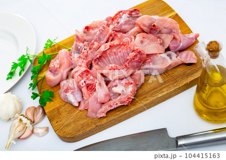 Raw sliced rabbit lying on wooden cutting board with seasonings 104415163