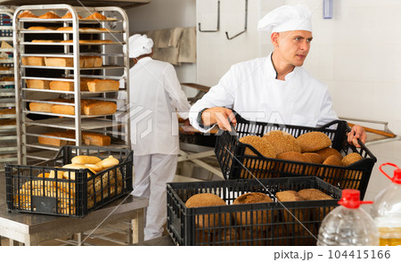 Male baker carrying crate with baked bread Male baker carrying crate with baked bread 104415166