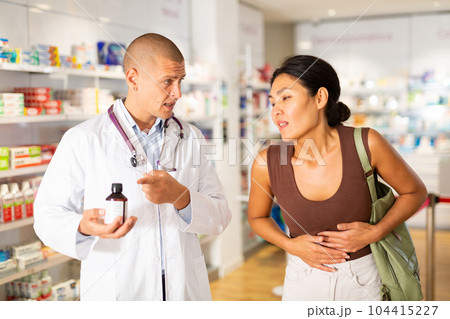 Pharmacist offering medicine for sore belly to patient at pharmacy closeup Pharmacist offering medicine for sore belly to patient at pharmacy closeup 104415227