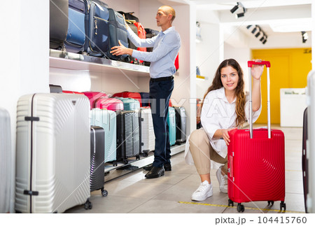 Young couple in a store chooses a travel suitcase 104415760