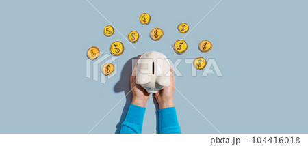 Person holding piggy bank with hand drawn coins 104416018
