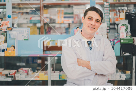 Male pharmacist posing confidently welcoming, advising patients and prescription patients in modern pharmacy. 104417009