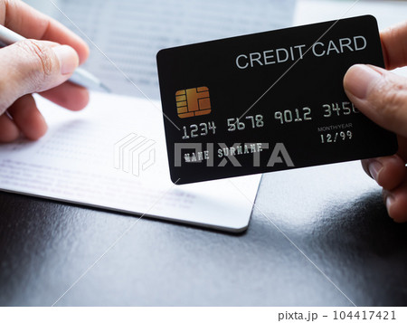 Finger Holding Credit Card with blur bank Account and Pen,Investment Income and Profit saving Cash Money and Tex,Shopping Purchase online,Business or Finance concept. 104417421
