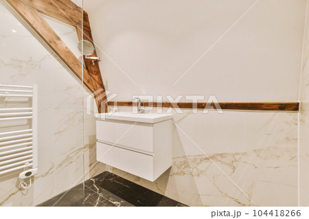 a bathroom with marble flooring and white walls, wood trim around the window simh is visible on the wall 104418266