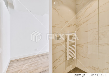 a modern bathroom with marble walls and floor to the right, there is a white towel rack on the wall a modern bathroom with marble walls and floor to the right, there is a white towel rack on the wall 104418308