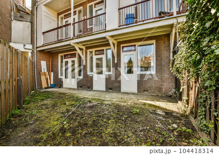 an outside view of a two story brick house with white doors and brown trim on the side of the building 104418314