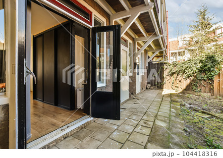an outside view of a house with black doors and brick walkway leading up to the front door on a sunny day 104418316
