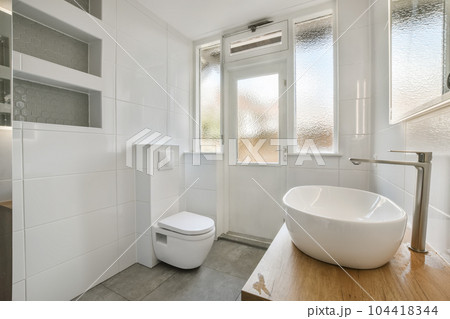 a bathroom with a sink, toilet and mirror on the wall next to the bathtub that is in front of the window a bathroom with a sink, toilet and mirror on the wall next to the bathtub that is in front of the window 104418344