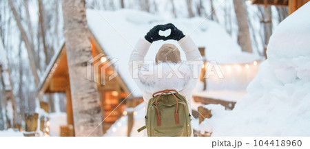 Woman tourist Visiting in Furano, Traveler in Sweater sightseeing Ningle Terrace Cottages with Snow in winter. landmark and popular for attractions in Hokkaido, Japan. Travel and Vacation concept Woman tourist Visiting in Furano, Traveler in Sweater sightseeing Ningle Terrace Cottages with Snow in winter. landmark and popular for attractions in Hokkaido, Japan. Travel and Vacation concept 104418960