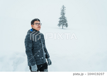 man tourist Visiting in Biei, Traveler in Sweater sightseeing Christmas tree with Snow in winter season. landmark and popular for attractions in Hokkaido, Japan. Travel and Vacation concept 104419207
