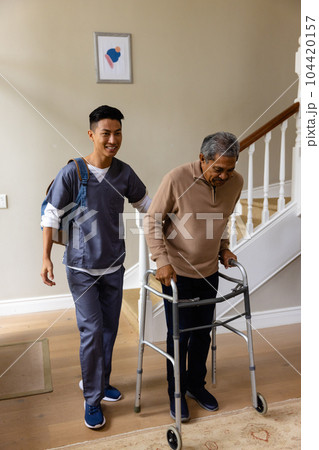 Diverse male doctor and senior male patient with crutches at home Diverse male doctor and senior male patient with crutches at home 104420157