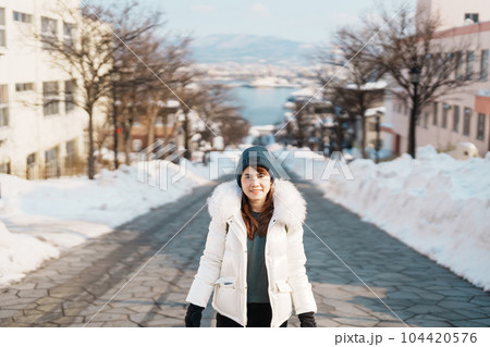 Woman tourist Visiting in Hakodate, Traveler in Sweater sightseeing Hachiman Zaka Slope with Snow in winter. landmark and popular for attractions in Hokkaido, Japan. Travel and Vacation concept 104420576