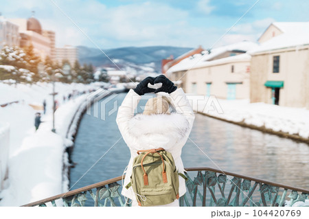Woman tourist Visiting in Otaru, happy Traveler in Sweater sightseeing Otaru canal with Snow in winter season. landmark and popular for attractions in Hokkaido, Japan. Travel and Vacation concept Woman tourist Visiting in Otaru, happy Traveler in Sweater sightseeing Otaru canal with Snow in winter season. landmark and popular for attractions in Hokkaido, Japan. Travel and Vacation concept 104420769
