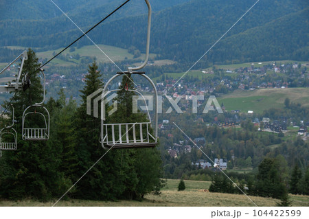 Ski Lift snowy mountain autumn forest with chair lift At The Ski Resort in Zakopane Poland. Holidays Vacation sport and outdoor activities tourism cable car empty seat grass field in green forest on Ski Lift snowy mountain autumn forest with chair lift At The Ski Resort in Zakopane Poland. Holidays Vacation sport and outdoor activities tourism cable car empty seat grass field in green forest on 104422599