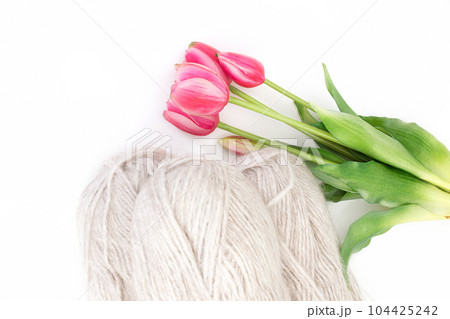 Group of gray wool of yarn and thread with pink tulip on white isolated background. Knitting, hobby, winter. Copy space. Top view. International women's and mother's day, 8 March, birthday Group of gray wool of yarn and thread with pink tulip on white isolated background. Knitting, hobby, winter. Copy space. Top view. International women's and mother's day, 8 March, birthday 104425242