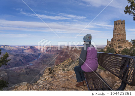 USA, Arizona, Rear view of female tourist sitting on bench in Grand Canyon National Park 104425861