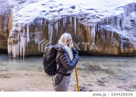 USA, Utah, Springdale, Zion National Park, Senior woman crossing river while hiking in mountains 104426039