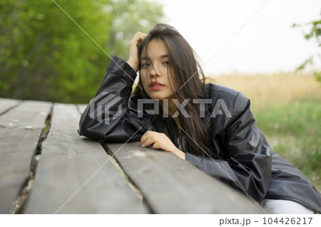 Portrait of teenage girl (16-17) leaning on picnic table 104426217