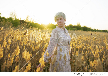 Portrait of woman standing in field at sunset 104426257