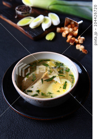 Fresh fish soup in a bowl on a black background, top view. White bread crackers. White fish soup. Transparent broth. A healthy dish. Lean menu.Vertical photo.Space for copying.Selective focus. Fresh fish soup in a bowl on a black background, top view. White bread crackers. White fish soup. Transparent broth. A healthy dish. Lean menu.Vertical photo.Space for copying.Selective focus. 104426720