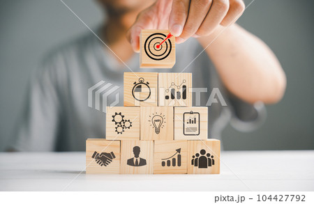 Hand stack of wooden blocks on a table, illustrating the concept of business strategy and action plan. Business development theme with copy space for creative customization. Hand stack of wooden blocks on a table, illustrating the concept of business strategy and action plan. Business development theme with copy space for creative customization. 104427792