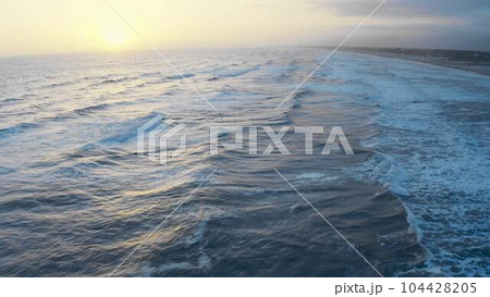 Sunset over ocean waves, flying over the sea during golden hour. Giant waves foaming and splashing in the sea. Cinematic drone shot, sunset wavy seascape Sunset over ocean waves, flying over the sea during golden hour. Giant waves foaming and splashing in the sea. Cinematic drone shot, sunset wavy seascape 104428205