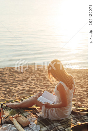 Young woman reading a book at the beach. Back view Young woman reading a book at the beach. Back view 104429075