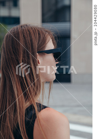 Side view photo of young woman in sunglasses outdoors in city 104429080