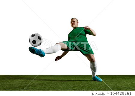 Concentrated young man, football, soccer player in uniform training, kicking ball with leg against white background Concentrated young man, football, soccer player in uniform training, kicking ball with leg against white background 104429261