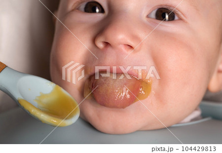 A small child of 5 months tries vegetable puree for the first time in his life, close-up 104429813