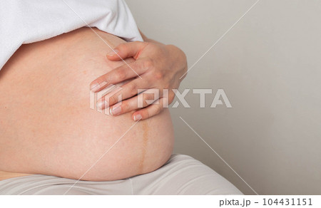 Pregnant girl sits and holds on to her stomach. The concept of love and affection for the future baby. Preparing for childbirth. Copy space for text Pregnant girl sits and holds on to her stomach. The concept of love and affection for the future baby. Preparing for childbirth. Copy space for text 104431151