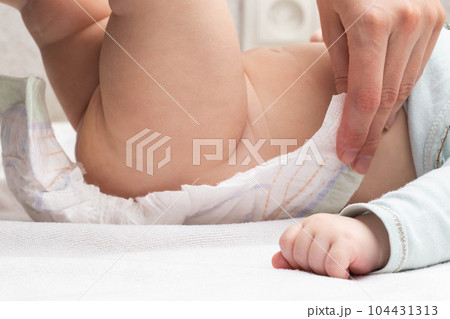 The mother fastens the fasteners and changes the baby's diaper, close-up. Copy space for text The mother fastens the fasteners and changes the baby's diaper, close-up. Copy space for text 104431313