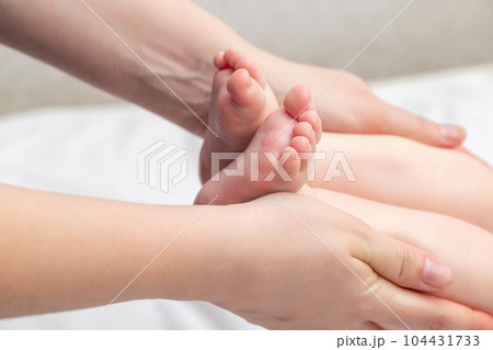 Mother massages baby on legs. Newborn skin care, close-up Mother massages baby on legs. Newborn skin care, close-up 104431733