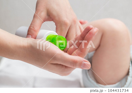 The mother applies a moisturizing cream with oil to the baby's skin so that the body does not become dry. Hygiene and skin care of the newborn. 104431734