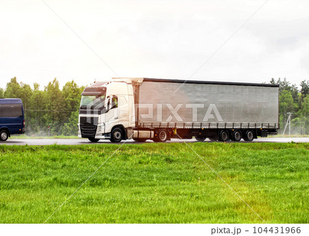 A tilt truck transports cargo on a highway in rainy weather on a slippery road. The concept of import substitution. Copy space for text A tilt truck transports cargo on a highway in rainy weather on a slippery road. The concept of import substitution. Copy space for text 104431966