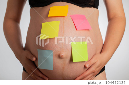 Blank multi-colored stickers are glued on the belly of a pregnant girl. In anticipation of the birth of a child, trimester. Copy space for text Blank multi-colored stickers are glued on the belly of a pregnant girl. In anticipation of the birth of a child, trimester. Copy space for text 104432123
