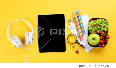 Tablet with blank screen, school supplies and lunch box Tablet with blank screen, school supplies and lunch box 104432611