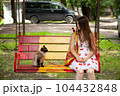 Color point cat being suspicious of its owner. Young lady trying to earn trust of her cat. An animal and a human sitting on a swing in a park, looking at each other inquiringly 104432848