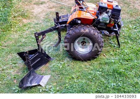 Plow and hiller complete with a walk-behind tractor for agricultural work. 104433093