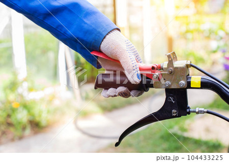 A man presses the handle of the safe shutdown of a walk-behind tractor with his hand during work. Copy space for text, running-in. 104433225