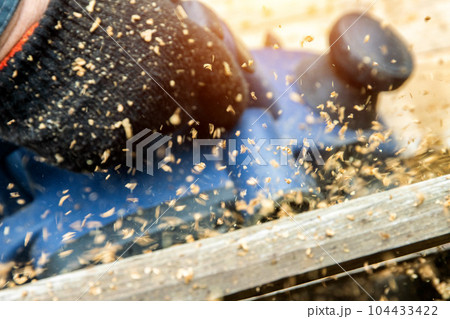 A man works with an electric tool with an electric planer, cleans old wood. Industry, close-up 104433422