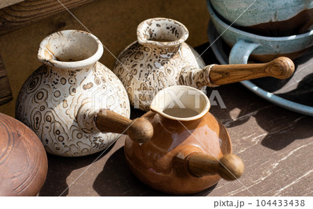 Clay and ceramic Turks with long handles for making coffee, close-up. Clay and ceramic Turks with long handles for making coffee, close-up. 104433438